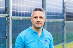 Portraitfoto von Next2Sun-Vorstand Heiko Hildebrandt in blauem Polo. Im Hintergrund vertikale Solarelemente.